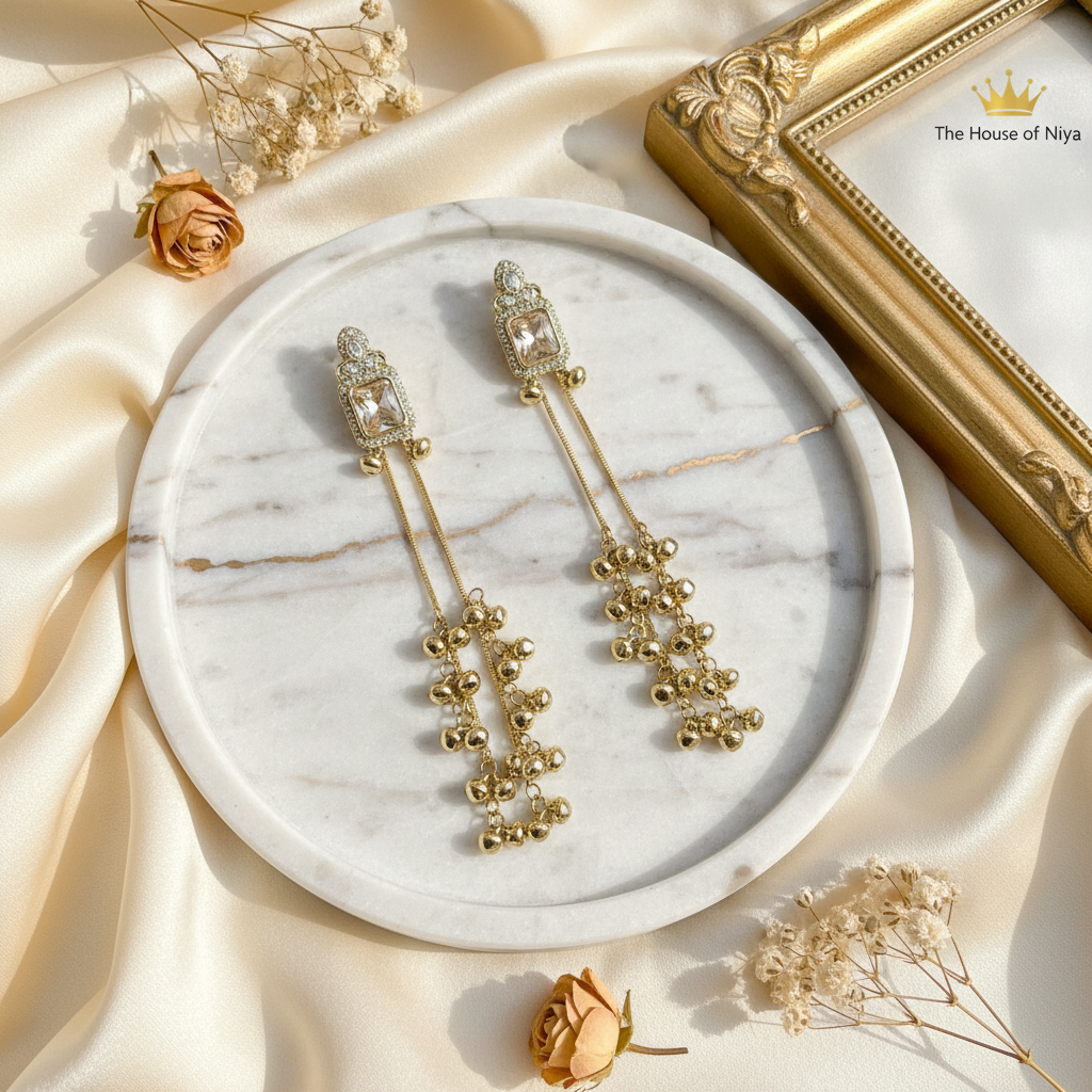 Gold ghungroo tassel drop earrings on marble tray