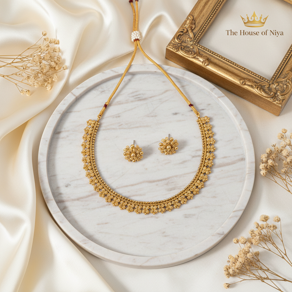 Gold floral cluster choker and stud earring set on marble tray