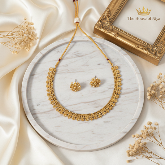Gold floral cluster choker and stud earring set on marble tray