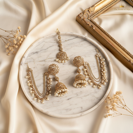 Gold filigree jhumka with pearl chain drops and tikka on marble tray