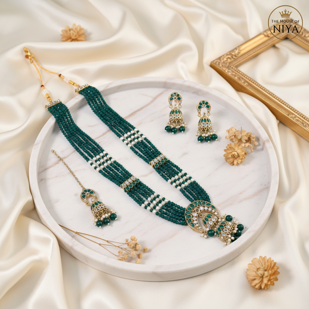 Emerald green crystal jhumka necklace, earring and tikka set on marble tray